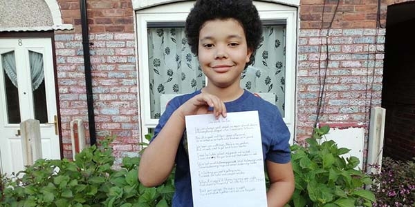 A boy holds up a poem about the coronavirus pandemic that he wrote. 