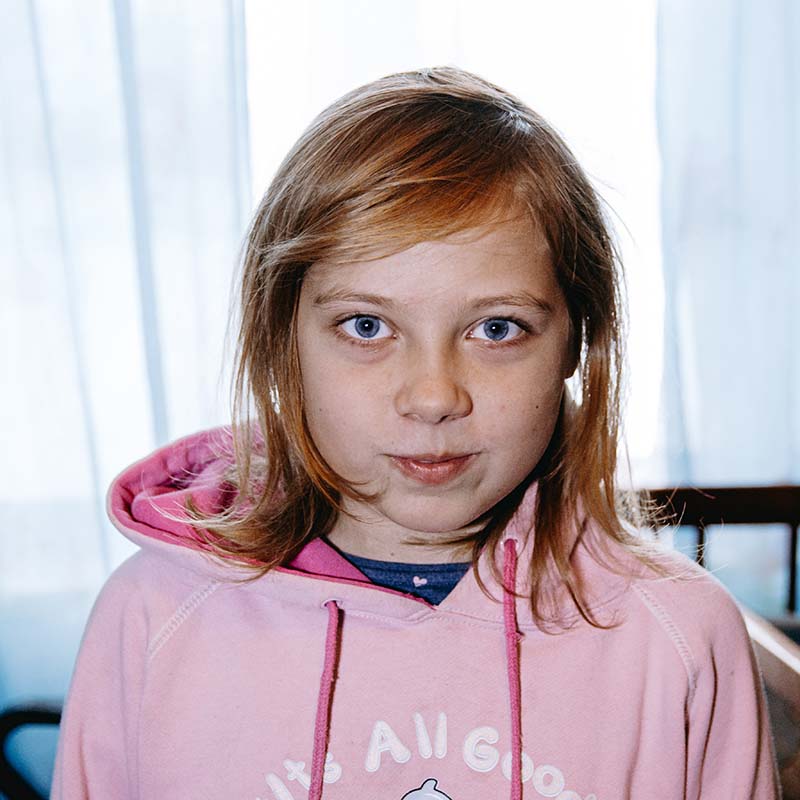 In Ukraine, a girl stands alone in her home which was damaged by shelling during the ongoing conflict.