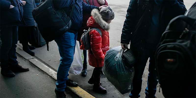 In Ukraine, a group of people stand in line outside in the cold. 