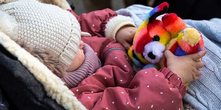  A Ukrainian refugee baby who has crossed the border into Romania to escape conflict holds a stuffed animal.