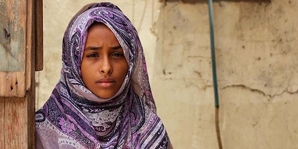 In Yemen, a girl sits alone outside. 