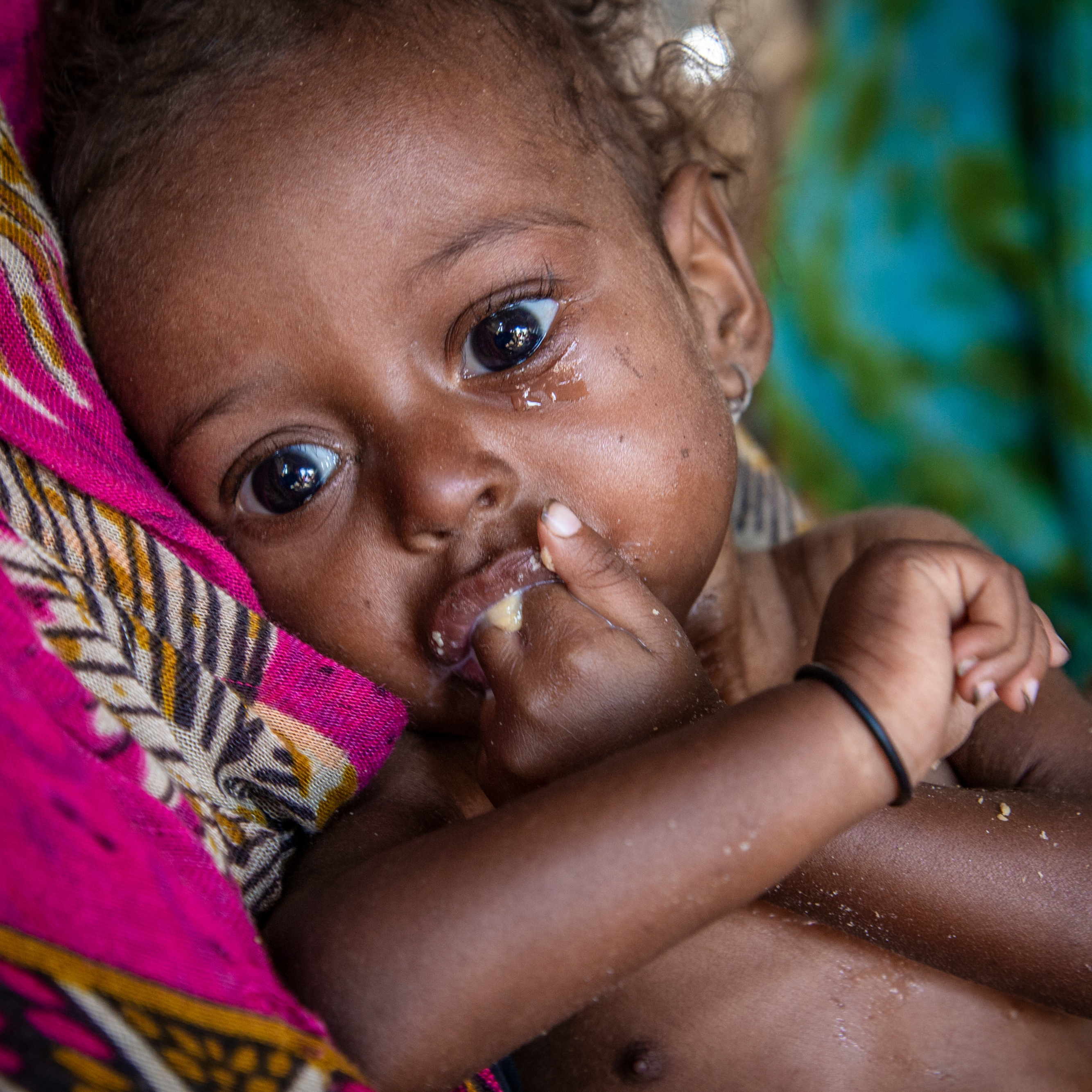 An 11-month old baby girl suffering from severe acute malnutrition eats a nutritious peanut paste given by a Save the Children health worker in a camp for Internally Displaced People (IDP) in Lahj district, Yemen. Photo credit: Jonathan Hyams / Save the Children, Nov 2018.