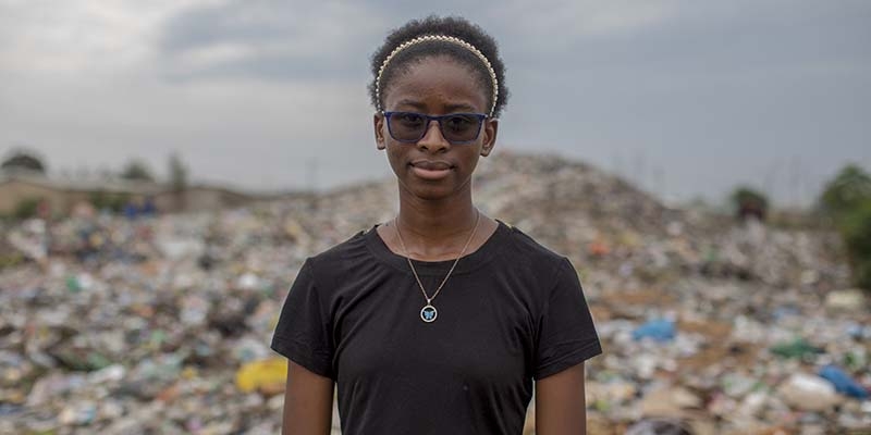 16-year-old Justina, a child climate activist, poses for the camera at the dumpsite in her community in Zambia