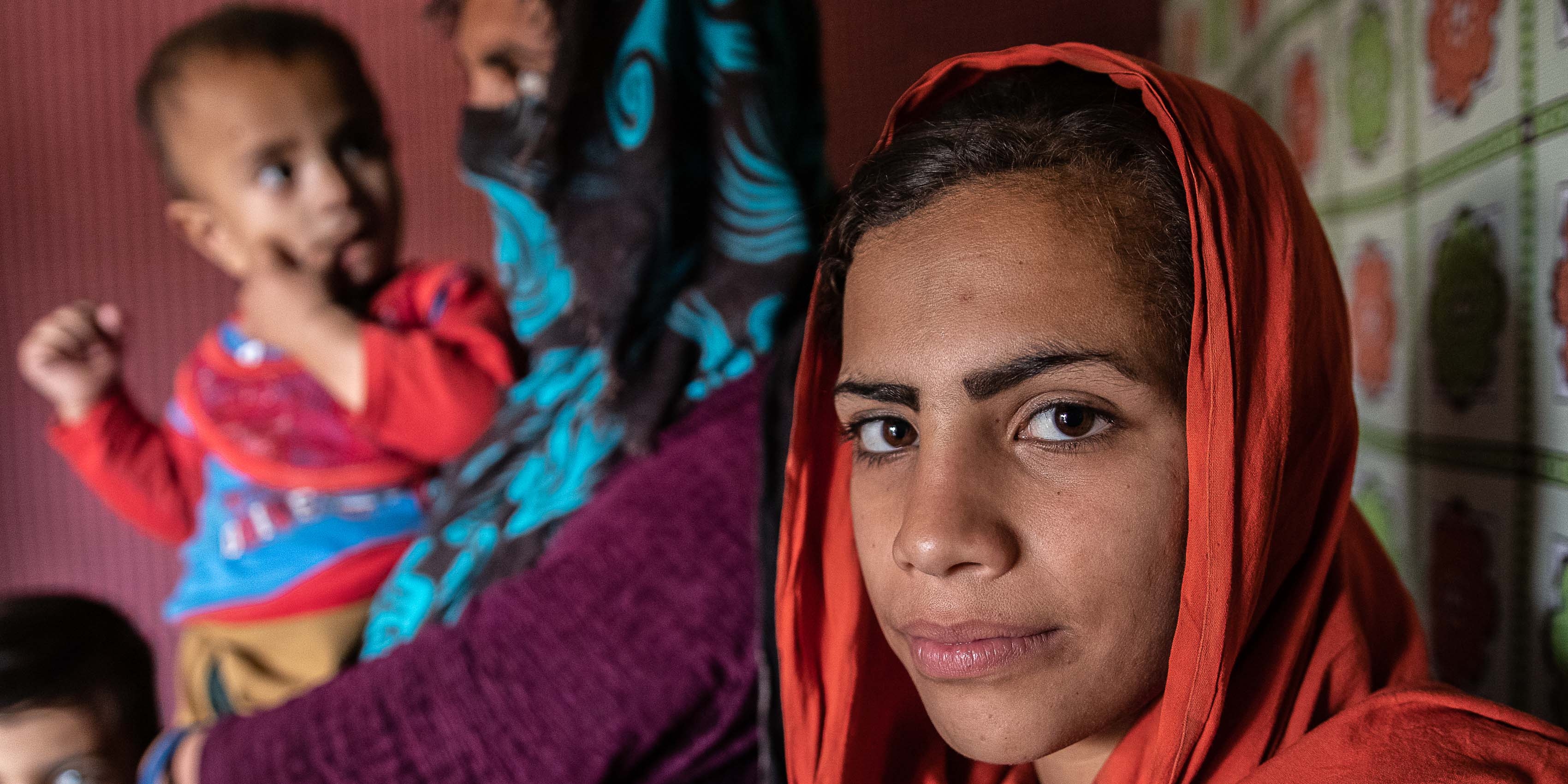 Afghanistan young girl looks to the camera wearing a orange hijab