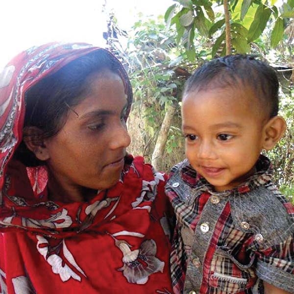 Little Hasabullah with a slight smile on his face is held by his mother in Bangladesh.