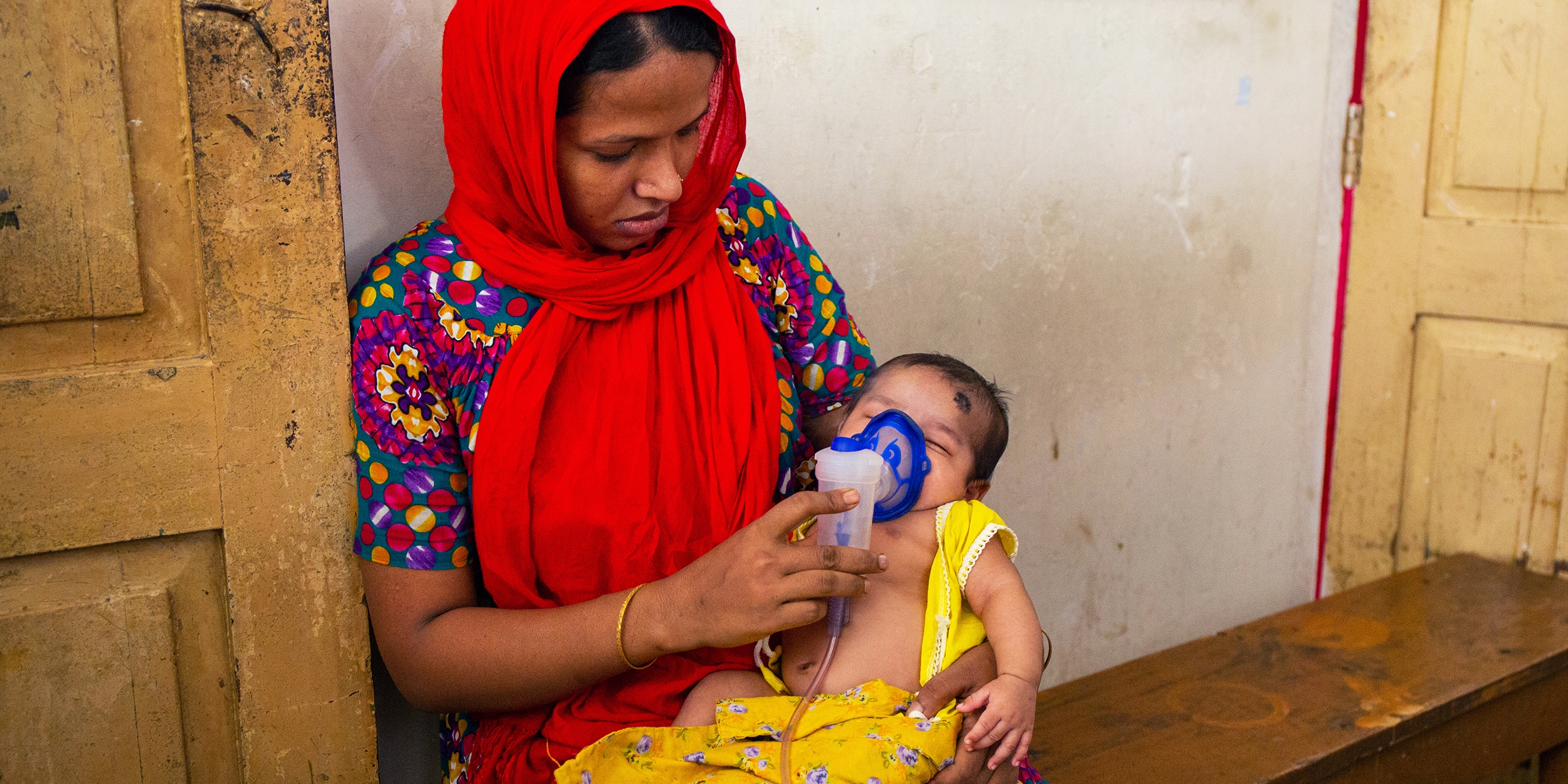 Bangladesh, a woman gives her infant a nebulizer treatment