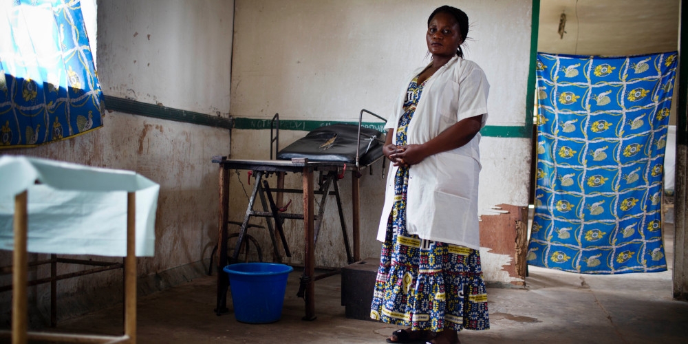 Bossello Menama Patience, 38, a midwife, stands near a bed at a mission hospital in Yusuku Kisangani, Democratic Republic of Congo. She received training through our Maternal and Child Health Program. Photo credit: Kate Holt/MCSP 2017.