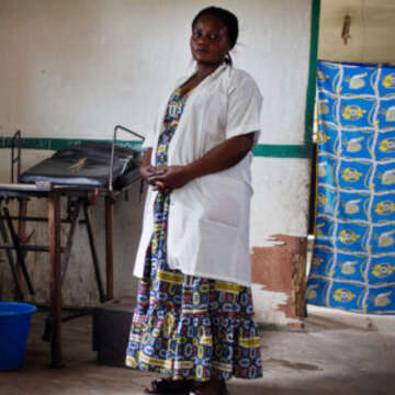 Bossello Menama Patience, 38, a midwife, stands near a bed at a mission hospital in Yusuku Kisangani, Democratic Republic of Congo. She received training through our Maternal and Child Health Program. Photo credit: Kate Holt/MCSP 2017.