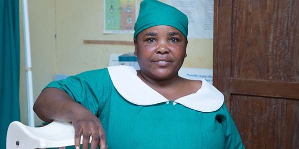 A healthcare worker living in rural Tanzania dressed in green scrubs.