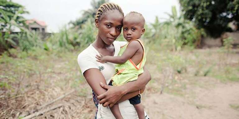  A mother holds her young African child, who suffered with pneumonia but was helped to recover, near a road in the Democratic republic of Congo.