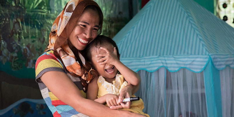 A mother holds her small child while smiling and laughing