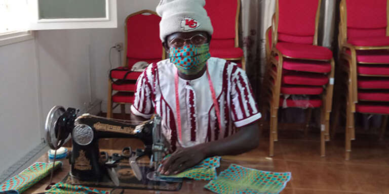 A woman in Mozambique using a sewing machine to stich a face mask to help her community prevent the spread of coronavirus