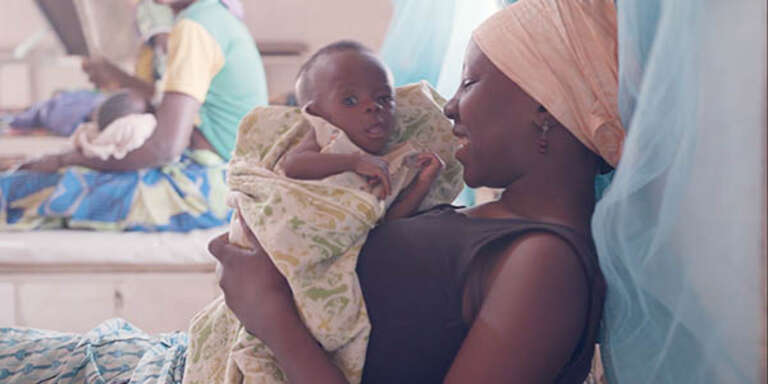 A mother holds her child in a hospital maternity ward.