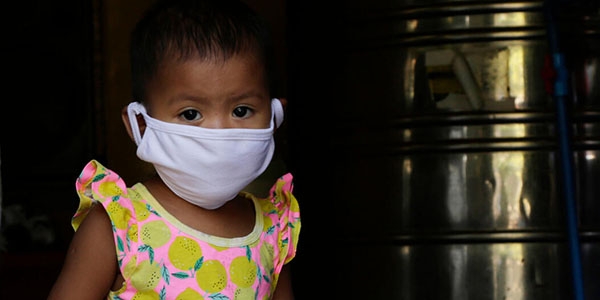  Althea*, 19 months, is pictured here wearing a mask at the water refilling station where her parents work.