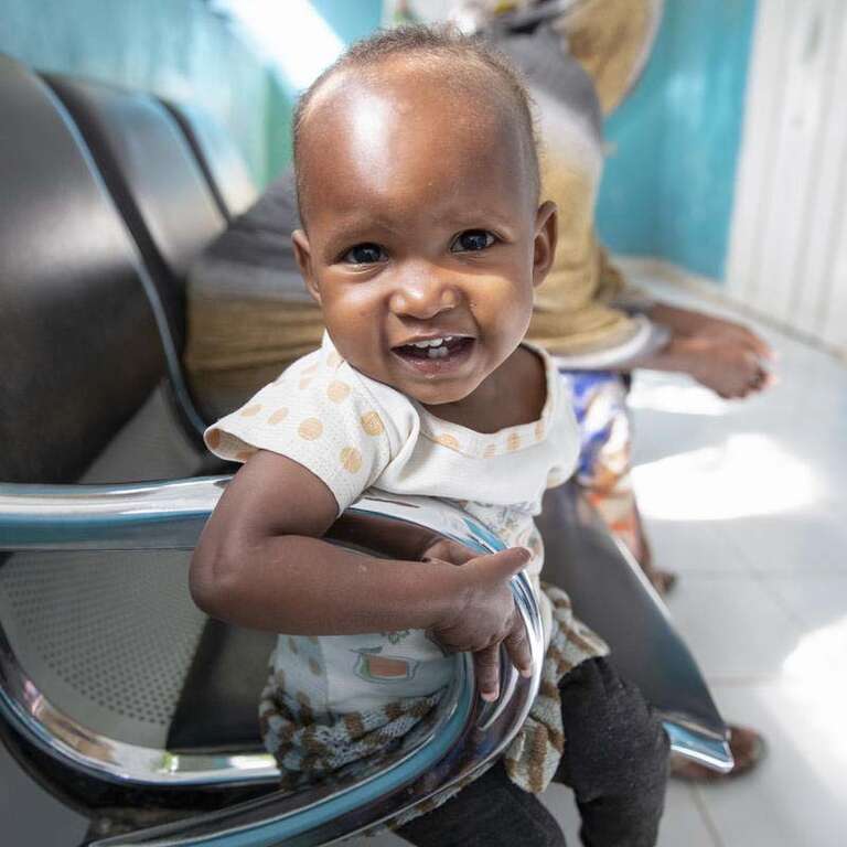 In Somalia, a baby laughs and smiles whil receiving medical care 