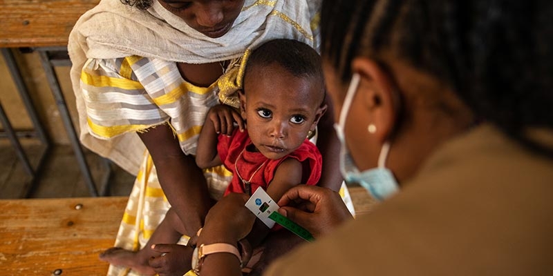 A young boy gets his arm measured by a health care worker in Tigray, Ethiopia.
