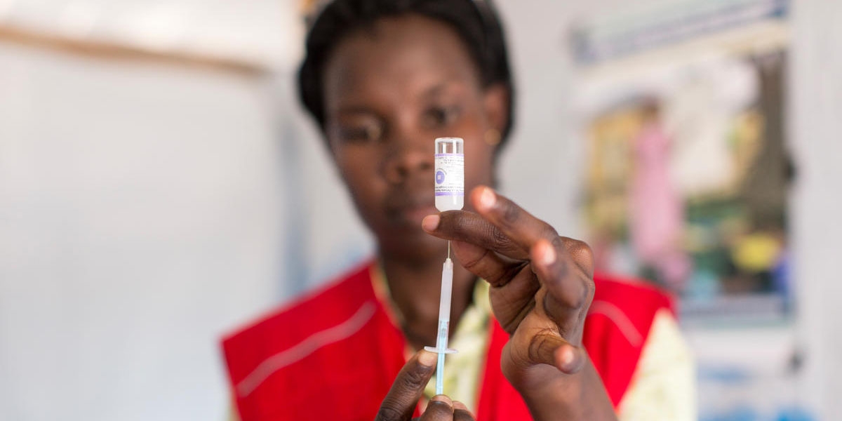 A Save the Children worker draws a vaccine needle.