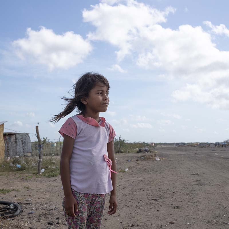Colombia, a little girl from Venezuela, stares out from her home settlement