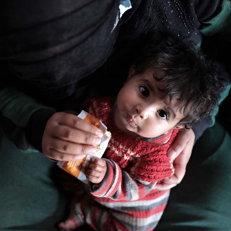 In Syria, a young child holds an emergency food pack.