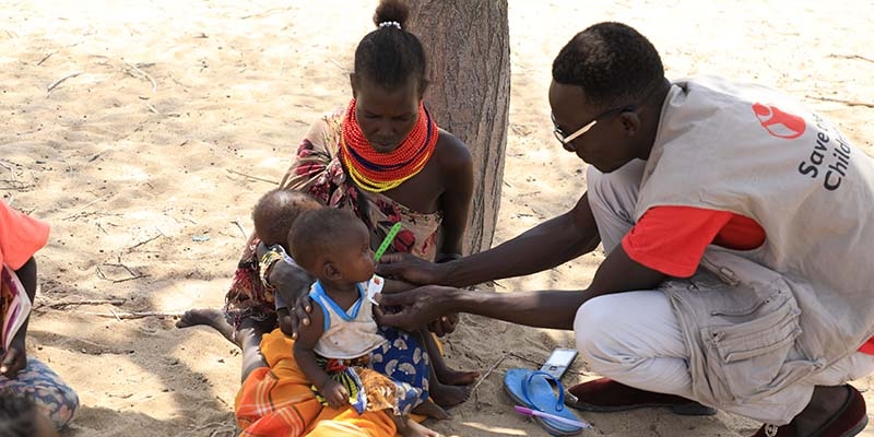 Kenya, a mother brings her 8-month-old twins to a Save the Children health check-up site