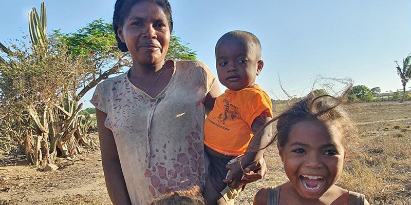 A woman in Madagascar holds a young child and three others stand in front of her.