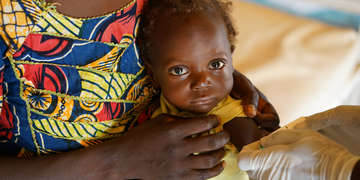 A 14-month old baby get measured with a MUAC (Mid-Upper Arm Circumference) band In her village in Douriou, Niger. Tehse small measuring tapes are used to assess the nutritional status of children aged from six months to five years. They are a crucial part of Save the Children’s malnutrition screening programs in Niger and beyond. Photo credit: Talitha Brauer / Save the Children, July 2016.