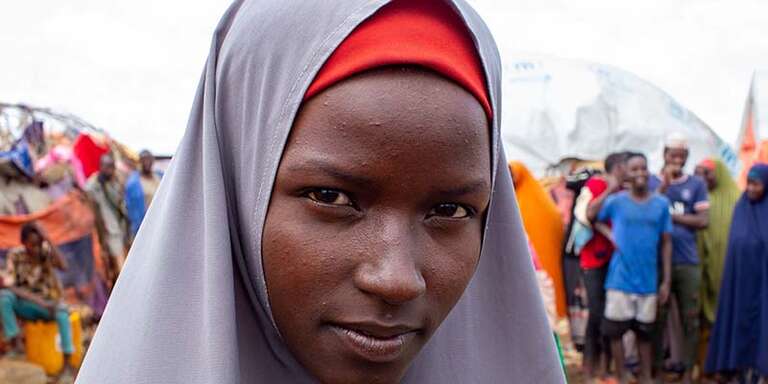 Somalia, a teenage girl stands in a displacement camp 