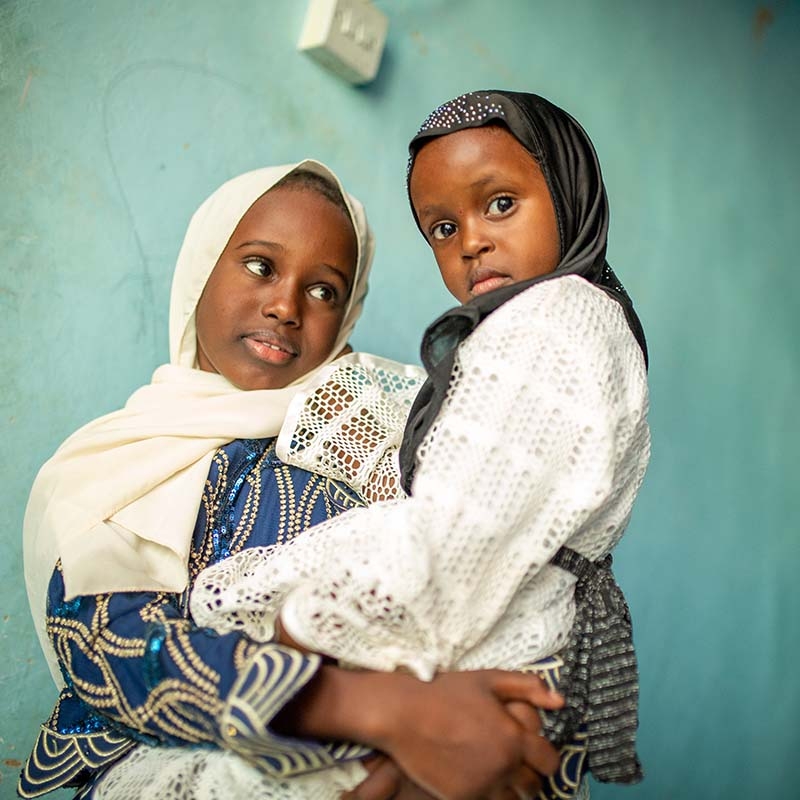 In Somalia, an older sibling holds her younger sibling in her arms. 