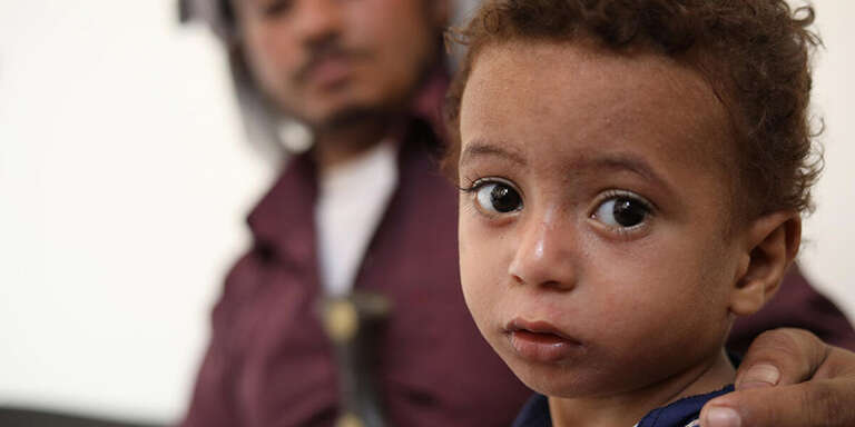 A boy in Yemen sits near an adult.