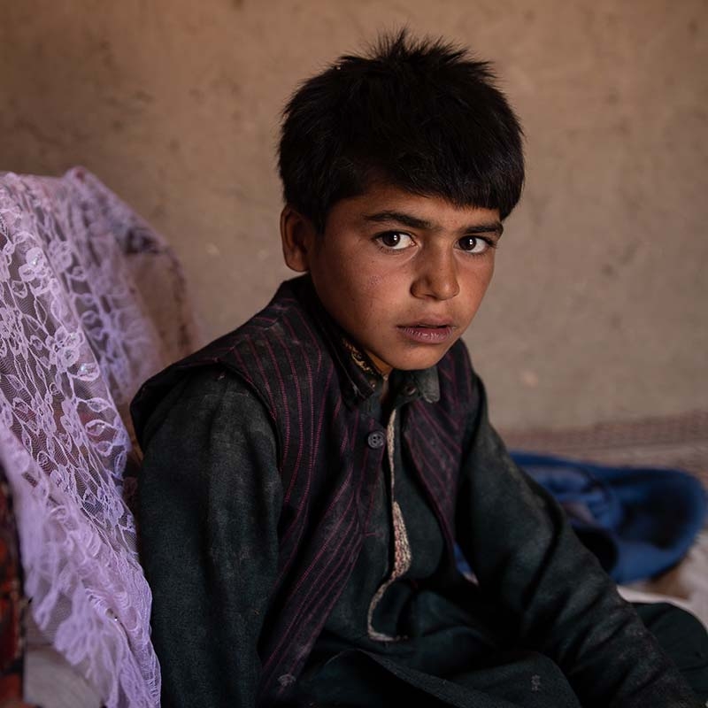 In Syria, a young boy looks pensive as he sits alone. 