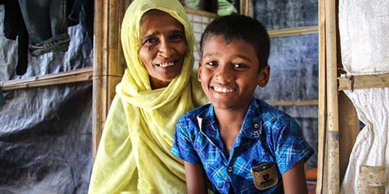 A 10-year old boy sits with his grandmother in a Rohingya refugee camp in Bangladesh.