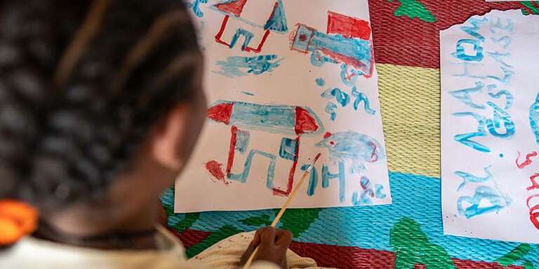 In Ethiopia, a child sits at a table and draws a picture as part of programming for children in conflict. 