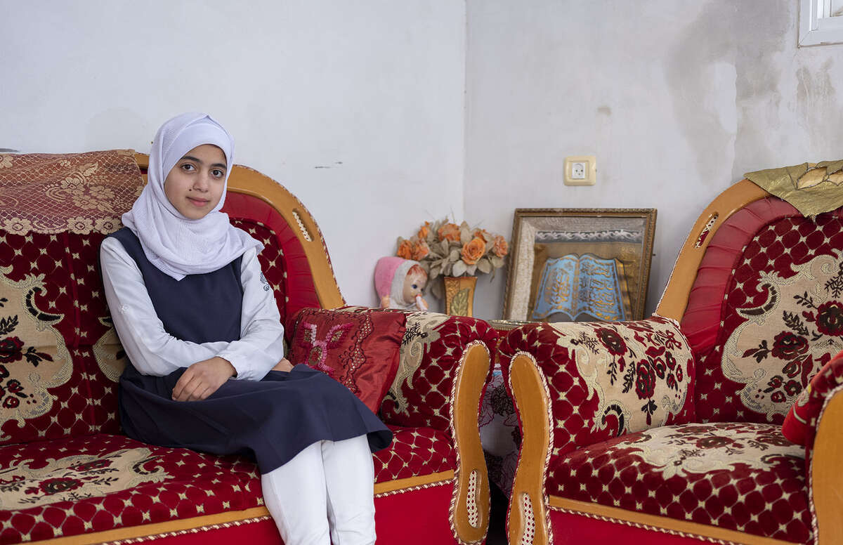 Gaza, a teen girl sits on a couch and looks at the camera