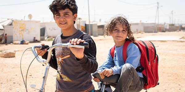 Young brothers take a break from a bicycle ride around the refugee camp where they live in Jordan.