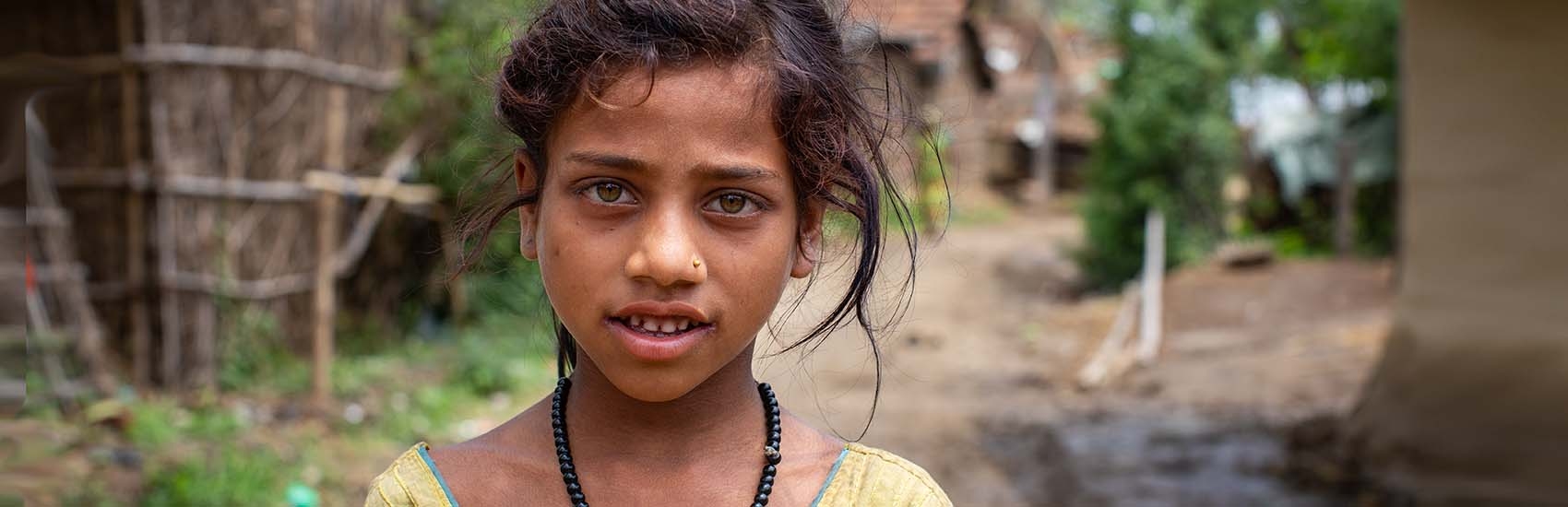An 8-year-old girls stands outside of her home in Nepal by herself.