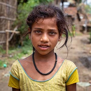 A girl stands outside her home in Nepal.