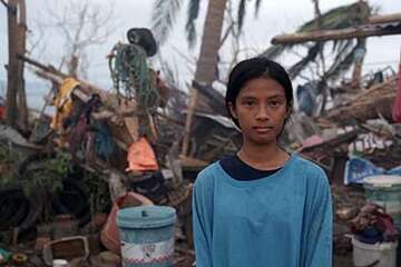 A 16-year old girl stands in front of a damaged structure destroyed by Typhoon Goni in the Phillipines. 