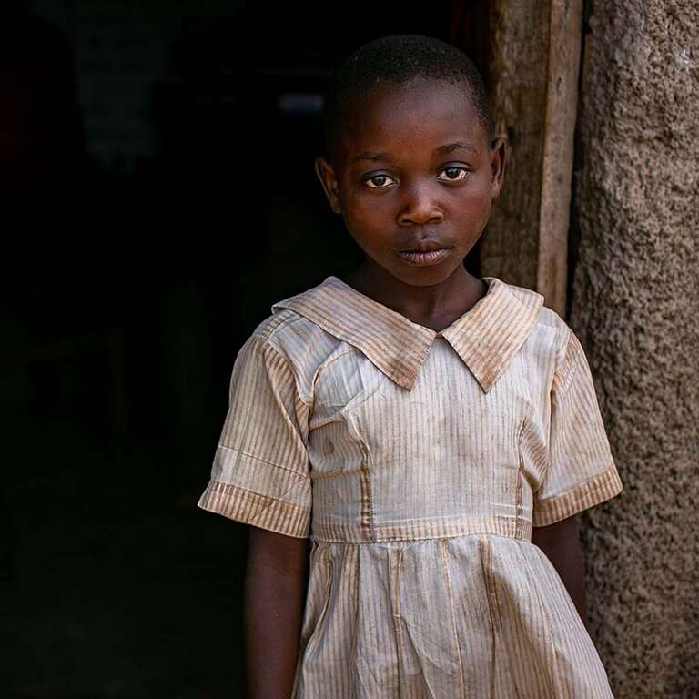 An 8-year-old girl stands outside of her primary school in the Kyangwali Refugee Settlement in Uganda. 