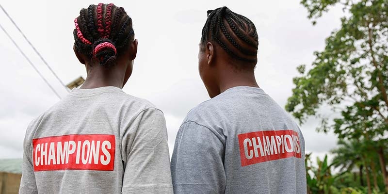 Two girls wear their "Ending Child Marriage Champion" t-shirts in Kailahun, Sierra Leone.