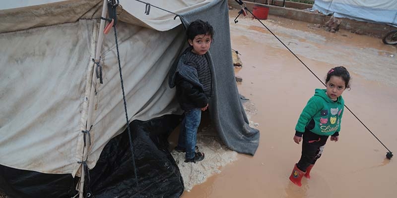 Two children stand in a flooded road out side of a tent in a displacement camp in North Western Aleppo, Syria.