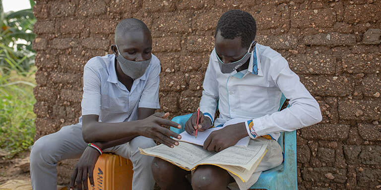 Jonathan*, 15 helping Peter, 15* to study. The boys are friends living in a refugee settlement for South Sudanese refugees in West Nile, Uganda.