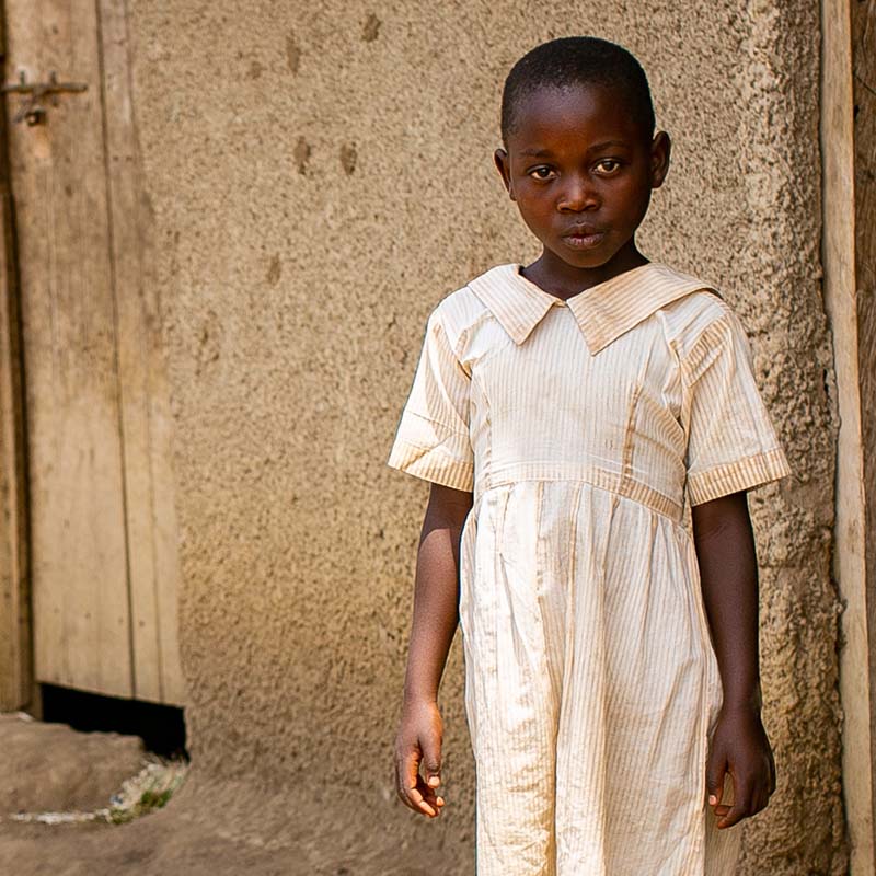 In Uganda, a young girl stands outside a home in a refugee settlement for displaced children and famliies who fled conflict in the DRC.