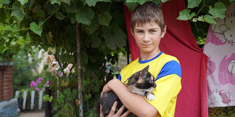 Ukraine,  a boy holds his cat outside his house in Kharkiv region, East Ukraine