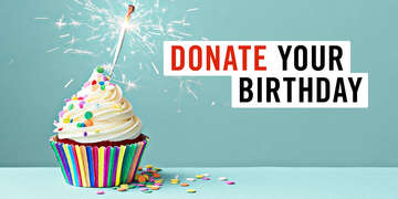 Multi-colored cupcake with sprinkles on a blue background with a sparkler instead of a candle. What is Donate Your Birthday? Instead of getting gifts on your birthday, ask your friends and family to donate to Save the Children instead. Photo credit: The Picture Pantry / Ruth Black / Getty Images, December 2018. 
