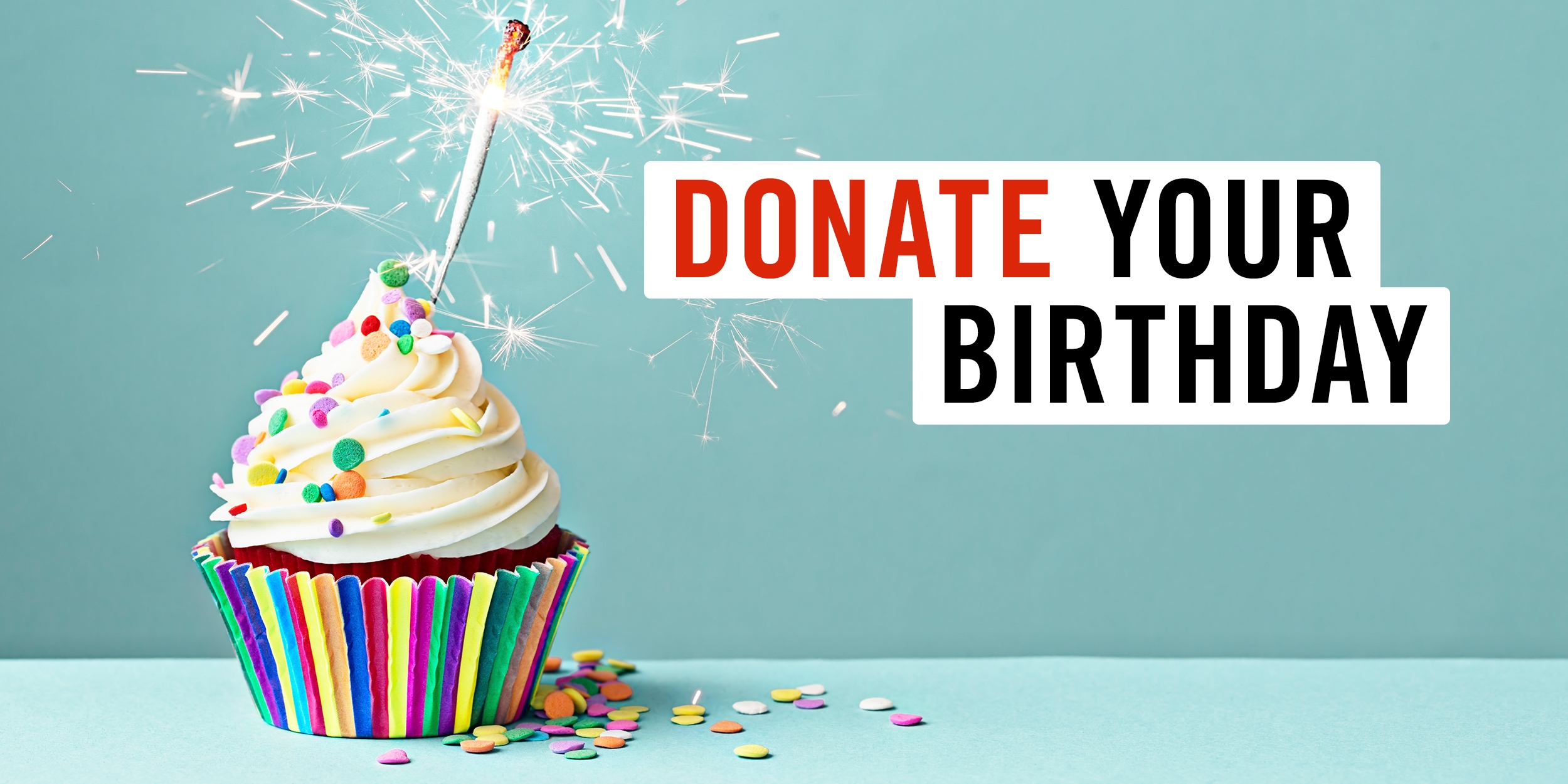 Multi-colored cupcake with sprinkles on a blue background with a sparkler instead of a candle. What is Donate Your Birthday? Instead of getting gifts on your birthday, ask your friends and family to donate to Save the Children instead. Photo credit: The Picture Pantry / Ruth Black / Getty Images, December 2018. 