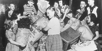 A black and white photo from 1941 depicting volunteers distributing donated clothing to needy children in the United States and war-affected Europe. Save the Children's first annual “Bundle Days” campaign in Knoxville, Tennessee is part of our 100-year history of doing whatever it takes for children in need. Photo credit: Save the Children 