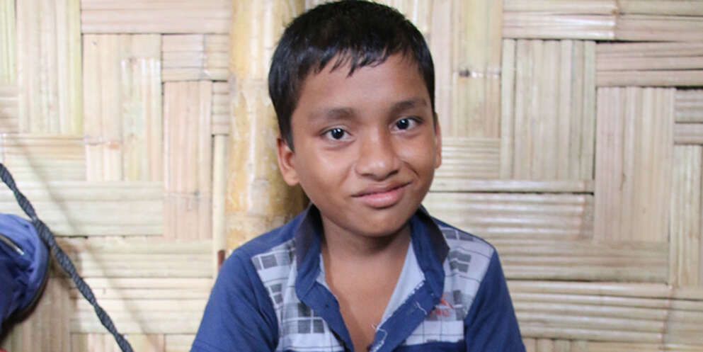 A boy from Bangladesh sits in his home