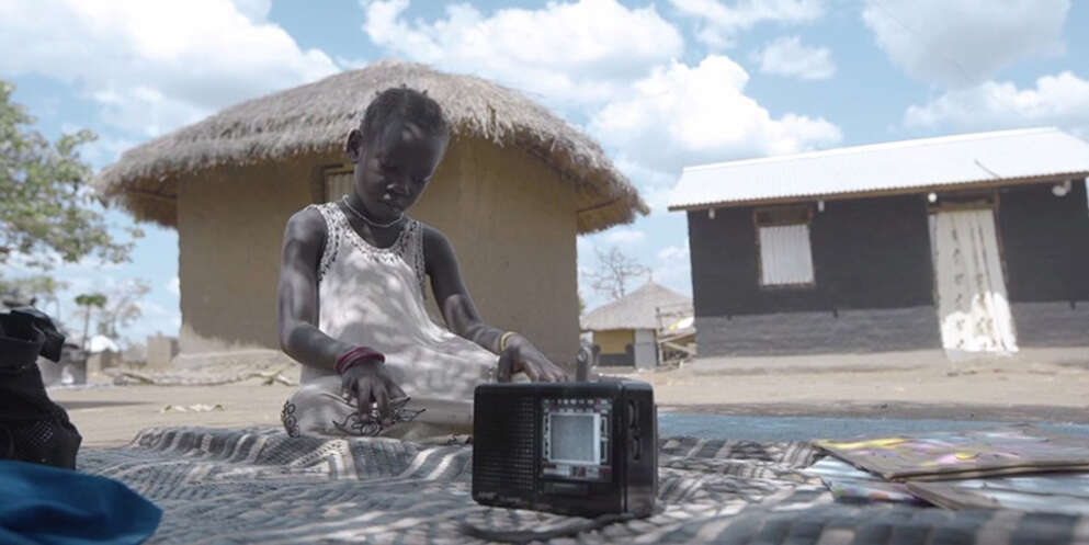 A girl from Uganda learns the alphabet by listening to the radio