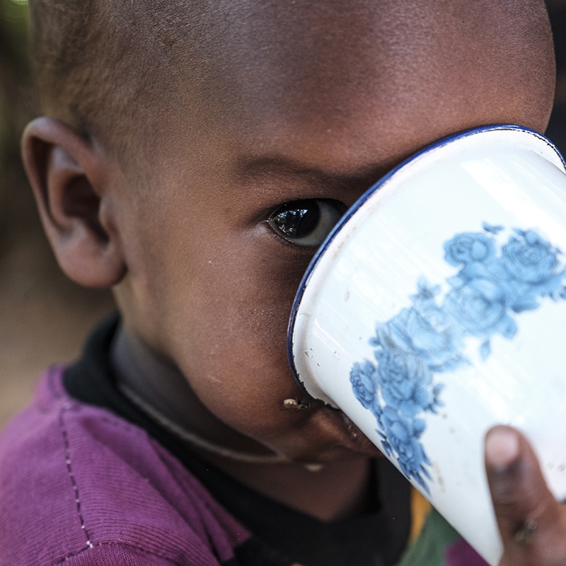 A child drinking from a cup. 