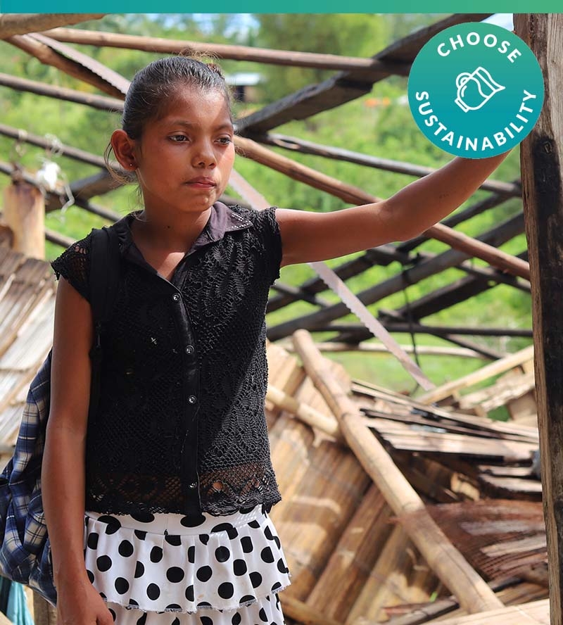 In Nicaragua, a girl stands outside of her home after it was destroyed by a violent storm. 